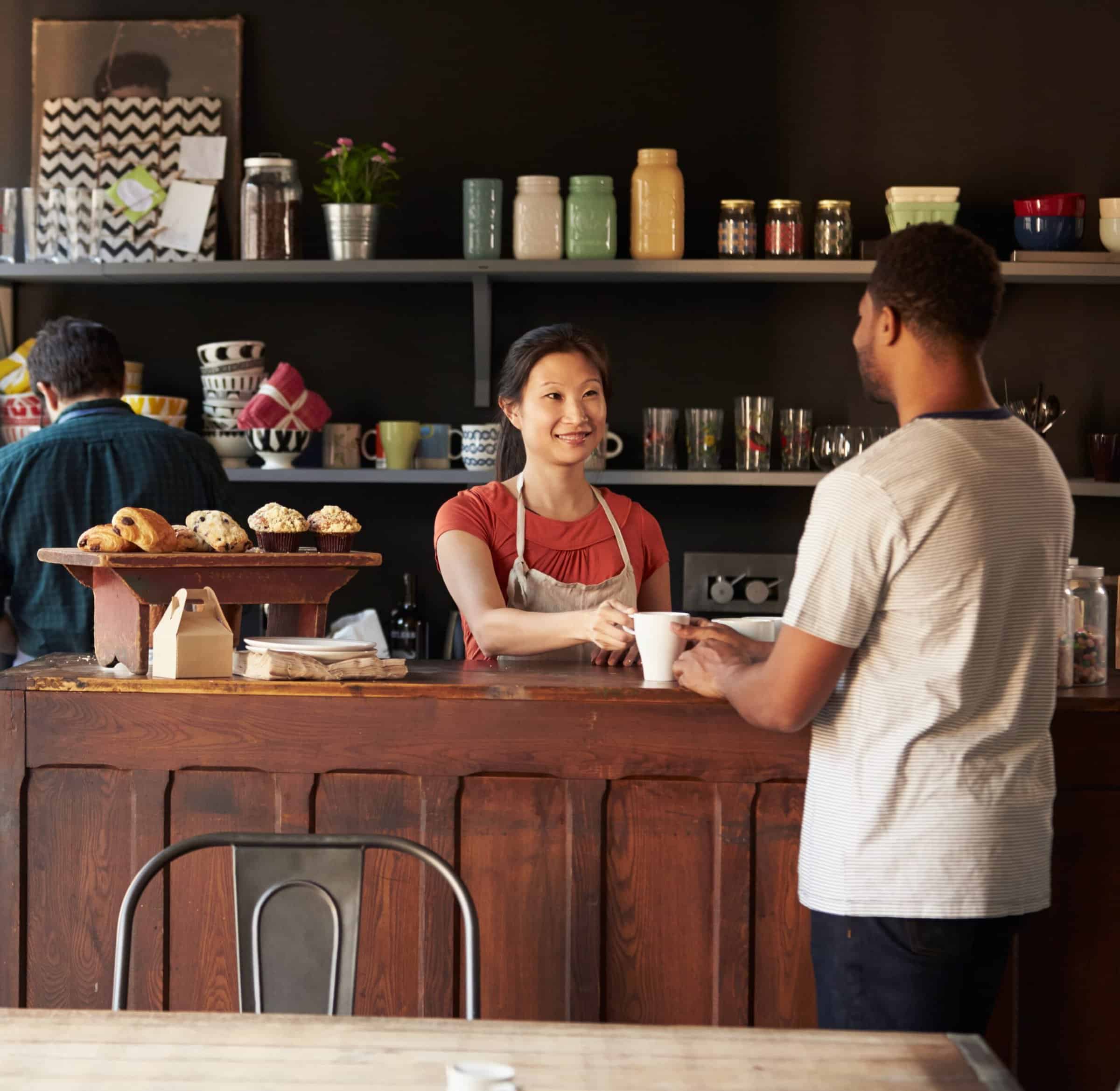 Staff Serving Customer In Busy Coffee Shop